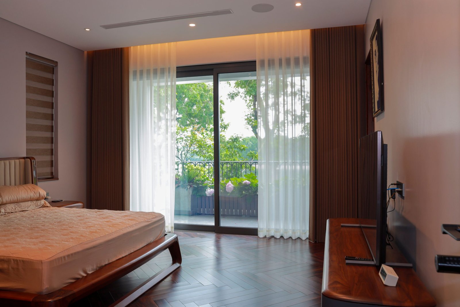 Interior of a peaceful bedroom featuring a bed and balcony views of lush greenery.